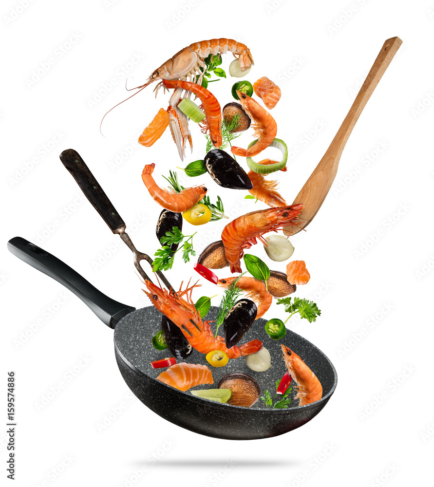 Fresh sea food and vegetables flying into a pan on white background