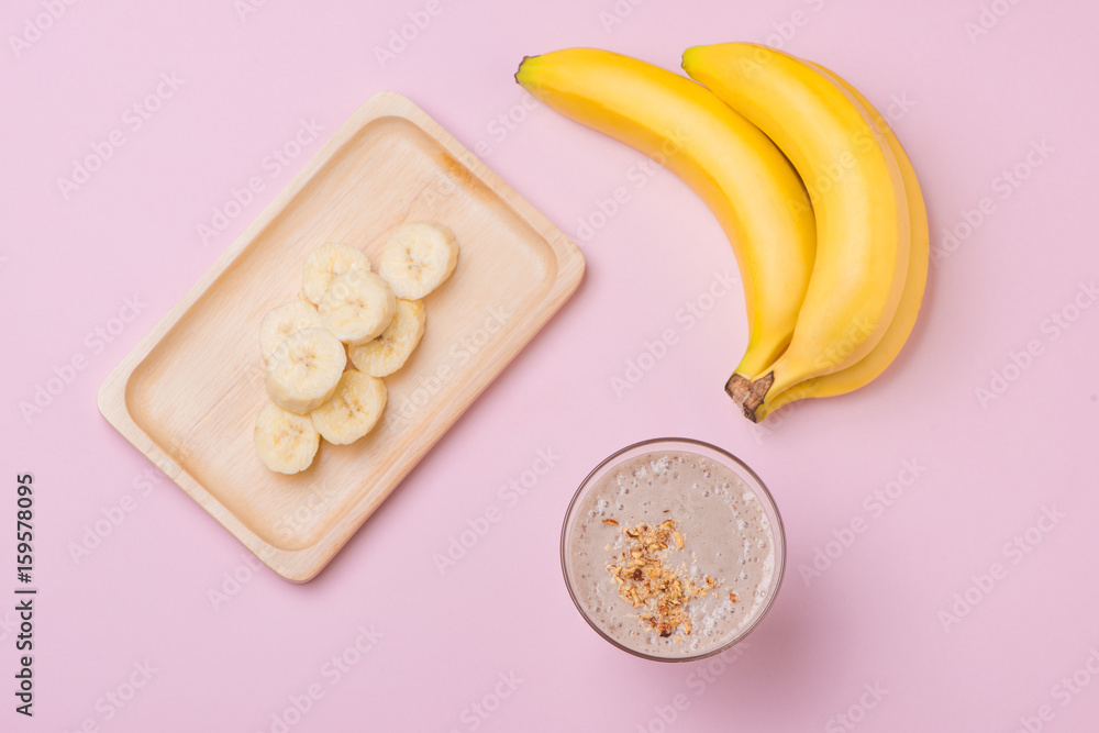 Fresh made banana smoothie in a glass on pink background