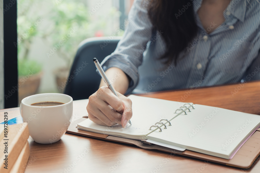 年轻漂亮女人坐在c位窗前的椅子上用笔记本写字的特写