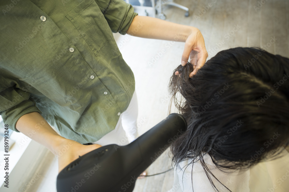 Hairdresser is drying womens long hair