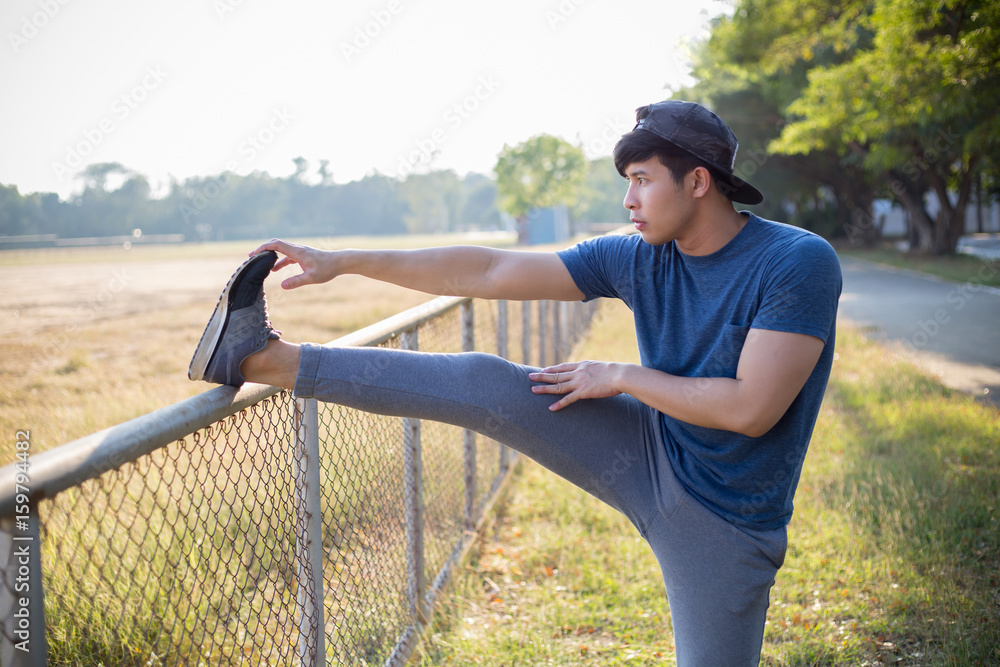 Young Asian man stretching his leg muscles before run