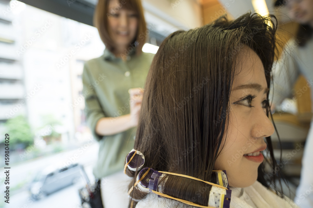 A woman is putting a perm in a hairdresser