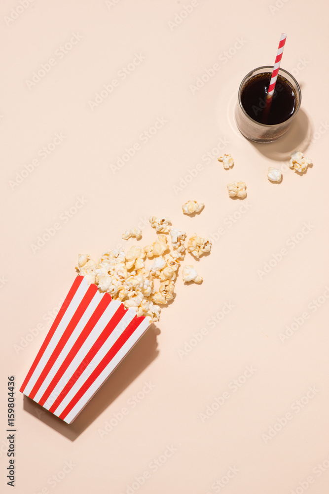 Popcorn in red and white cardboard with glass of soda