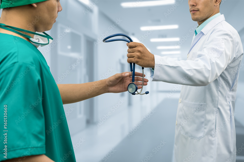 Doctor giving stethoscope to surgeon (Referral)