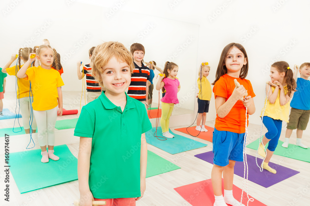 Happy kid boy playing jumping rope with friends