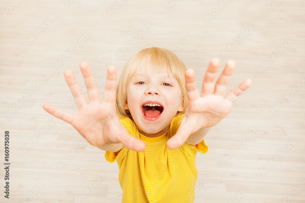 Joyful five years old boy lifting hands upward