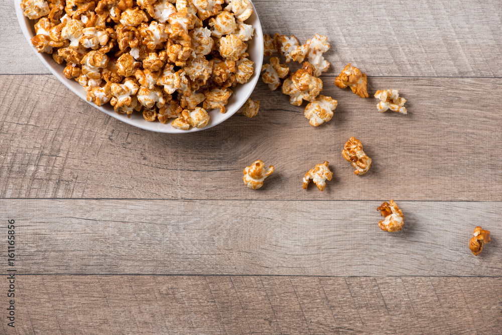 Caramel opcorn in bowl on the wooden table.