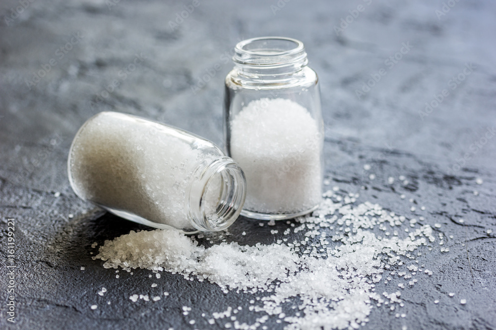 Spices set with salt in glass bottles for cooking on stone background