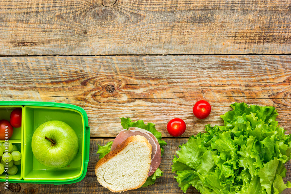 healthy break with apple, grape and sandwich in lunchbox on home table flat lay mock-up