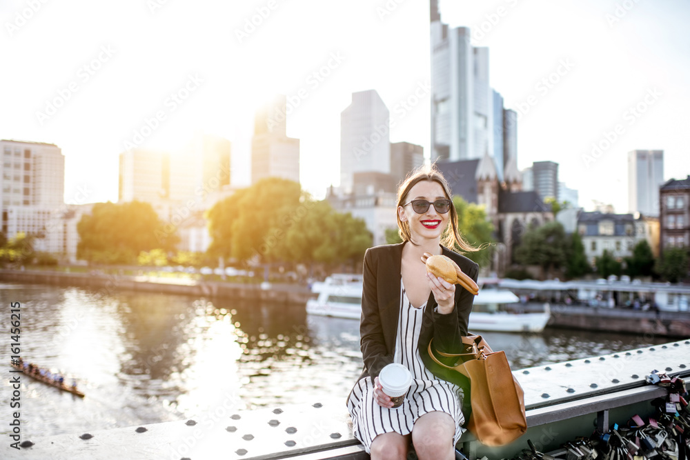 年轻的女商人在桥上用传统的法兰克福香肠和咖啡与s一起吃零食