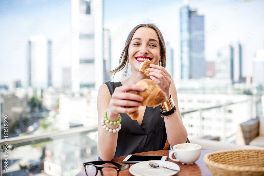 Young businesswoman having a breakfast outdoors with beautiful cityscape view at the modern district