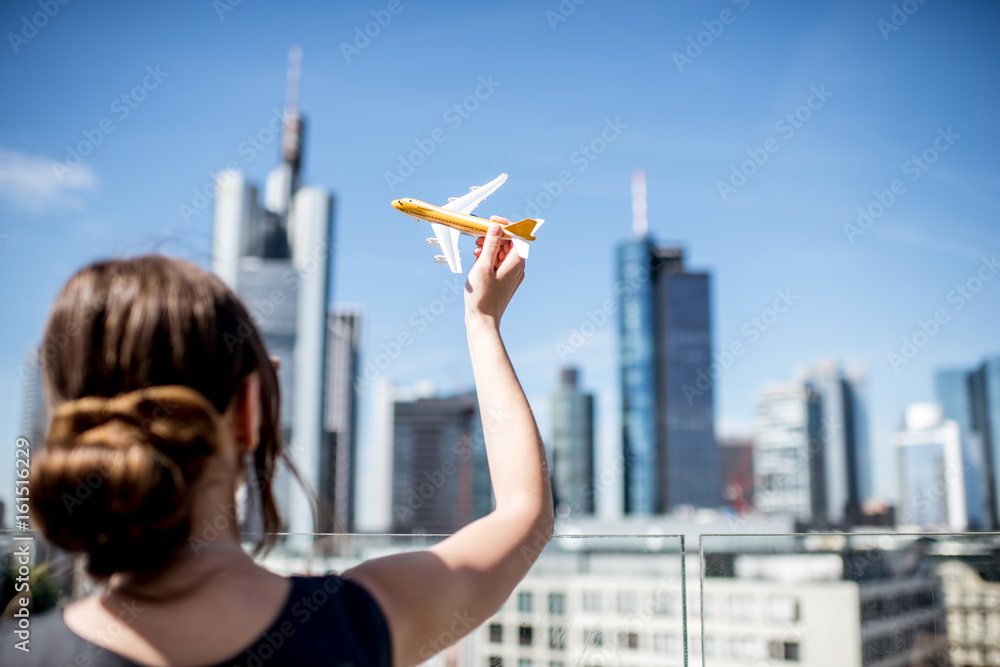 法兰克福现代城市景观背景下，一名年轻女子在玩玩具飞机。航空运输