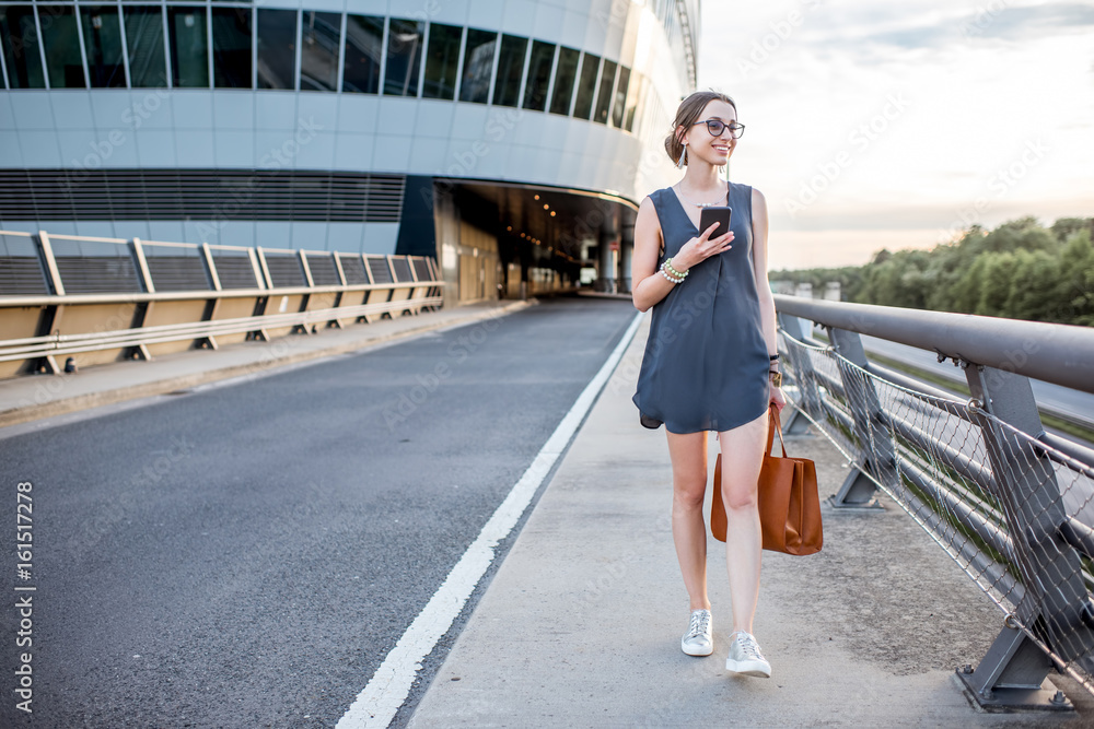 Young businesswoman walking with phone on the highway during the business trip