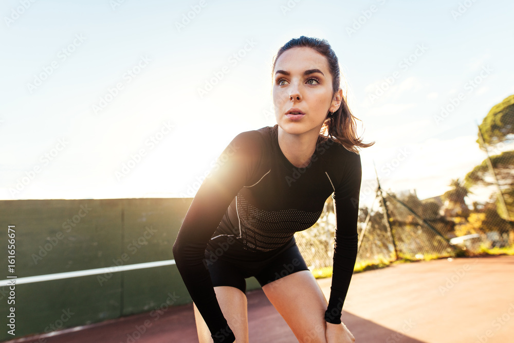 Beautiful woman resting after workout on tennis court