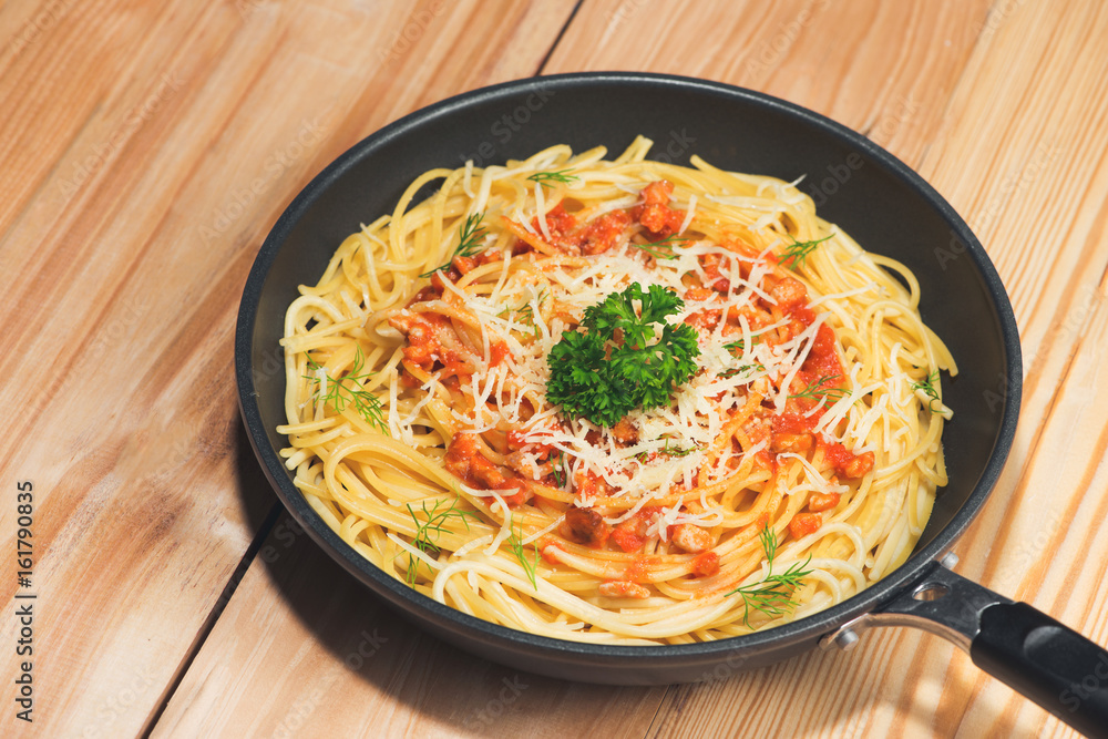 Tasty spaghetti with tomato sauce and meat in pan on wooden table.