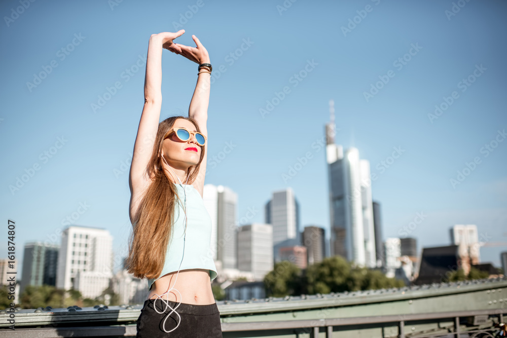 Young woman in sportswear stretching up on the beautiful modern city background in Frankfurt