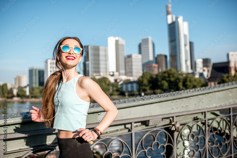 年轻女子晨练在美丽的现代城市铁桥上跑步