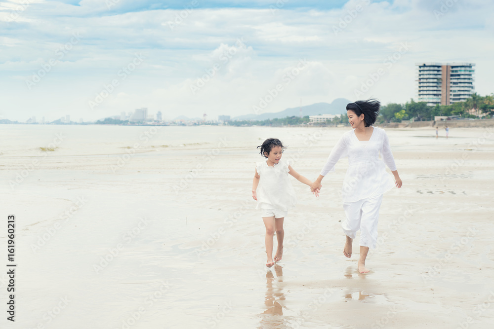 Happy Asian family mother and child daughter run, laugh and play at beach. Happy family summer vacat