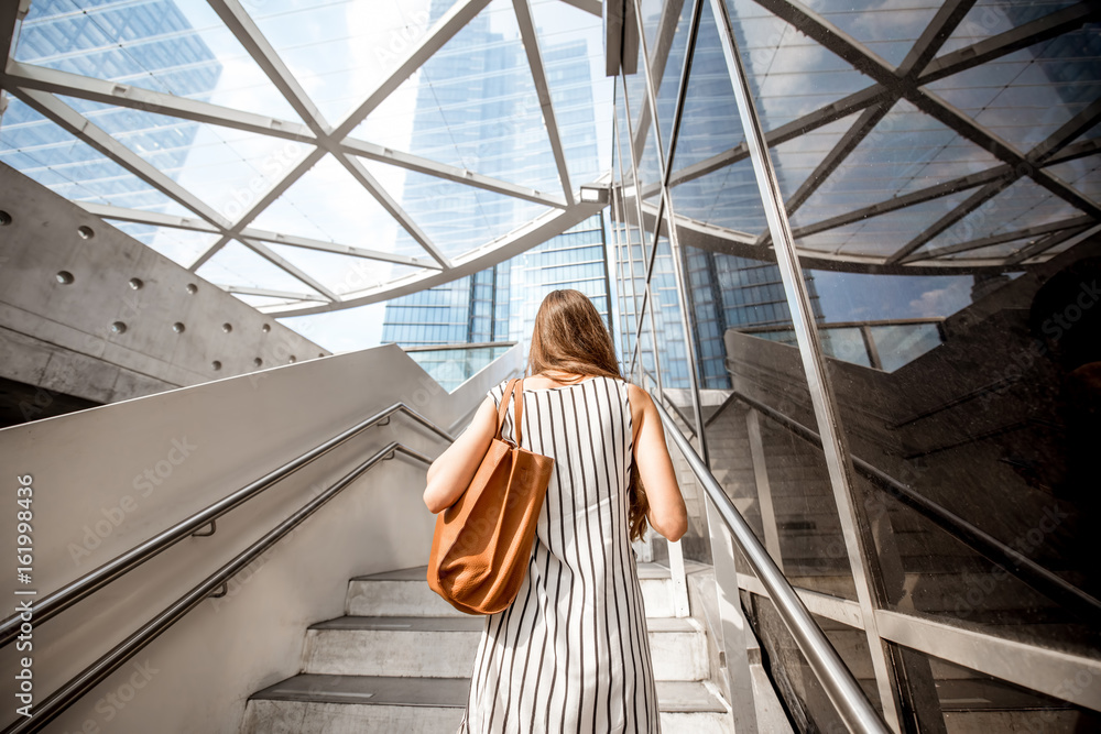 年轻漂亮的女商人走回户外，走在布鲁塞现代办公室附近的楼梯上