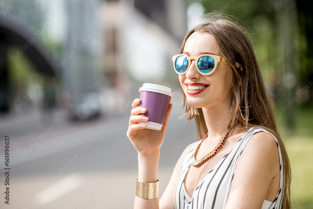 Young and smiling businesswoman having a coffee break standing outdoors on the street in Brussel cit