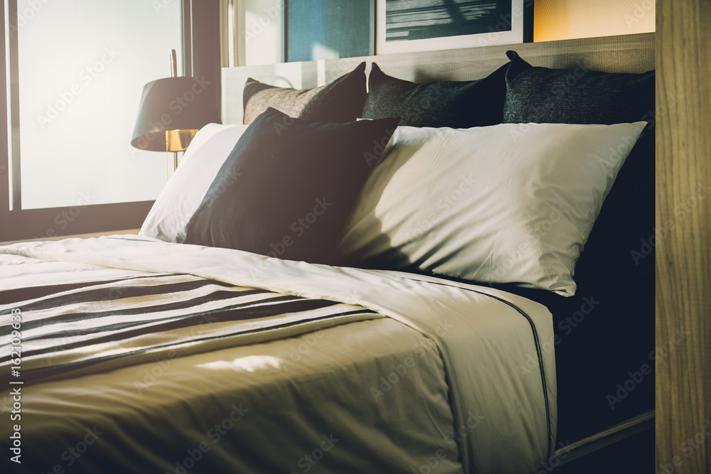 Bed maid-up with clean white pillows and bed sheets in beauty room. Close-up. Lens flair in sunlight