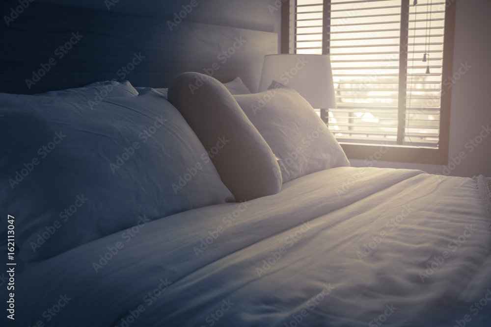 Bed maid-up with clean white pillows and bed sheets in beauty room. Close-up. Lens flair in sunlight