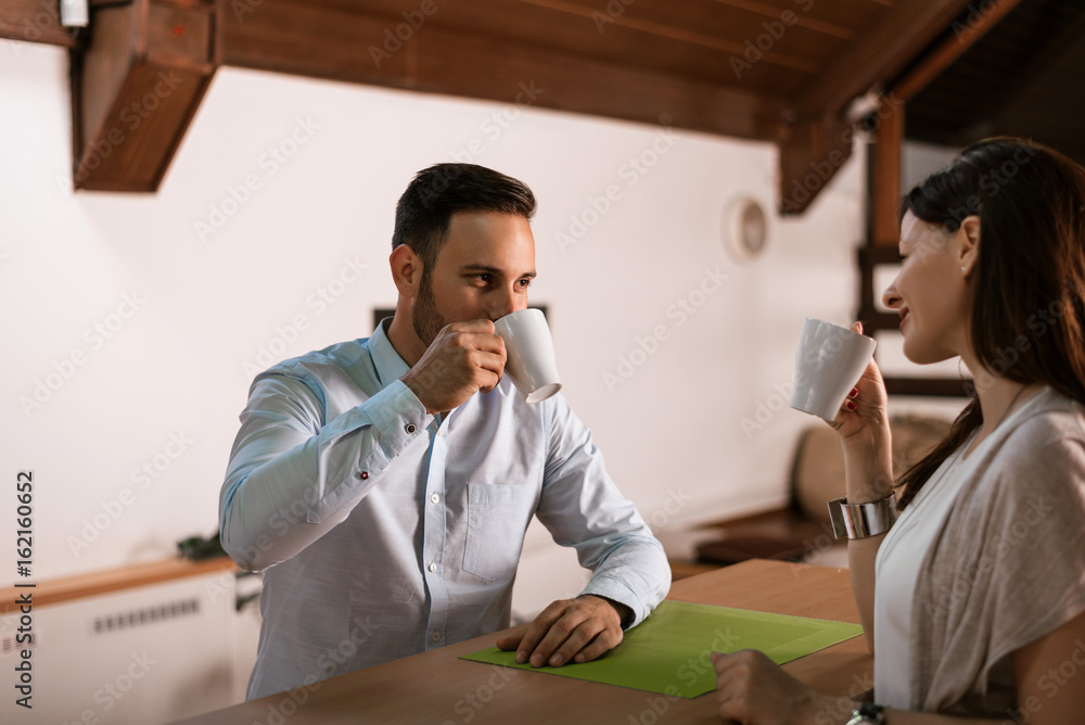 Happy young couple drinking coffee in living room