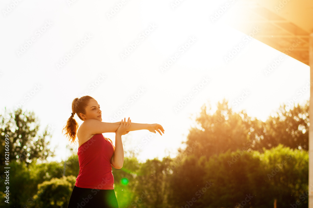 Portrait of a fitness woman doing warm up exercises outdoors