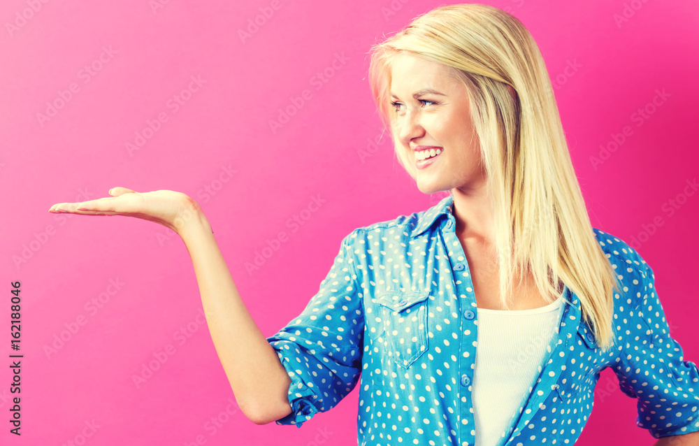 Young woman with a displaying hand gesture on a pink background