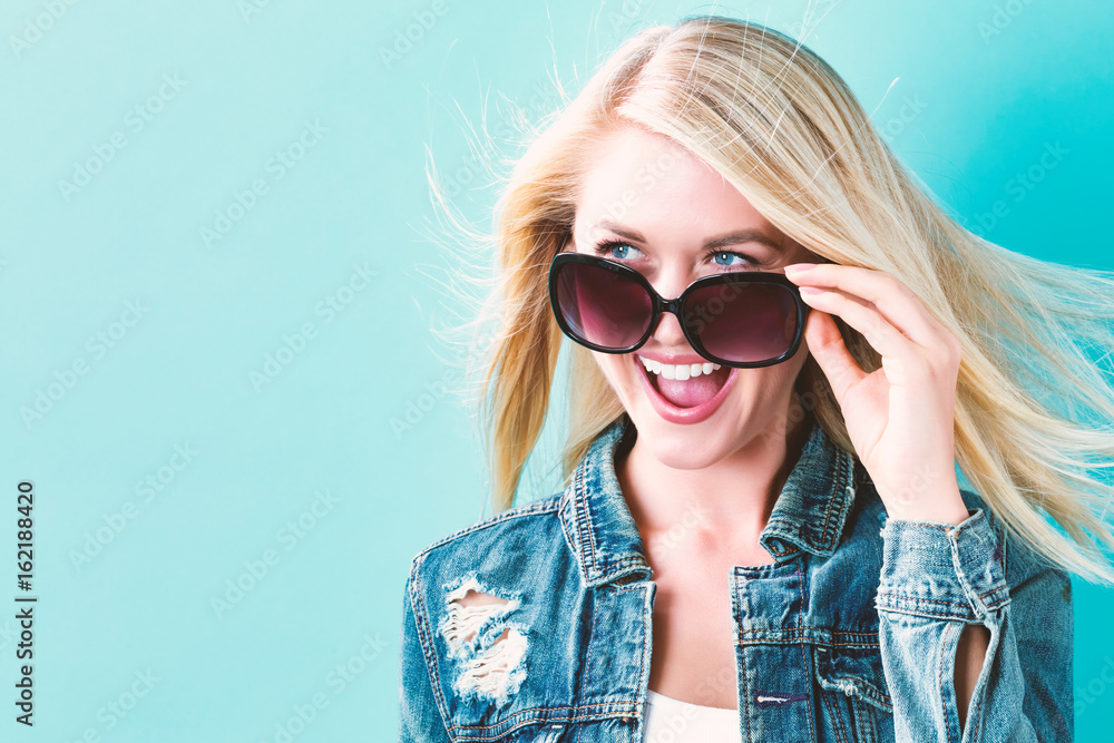 Young woman with sunglasses on a blue background