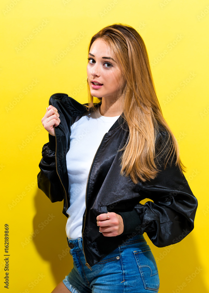 Girl wearing a black jacket on a yellow background