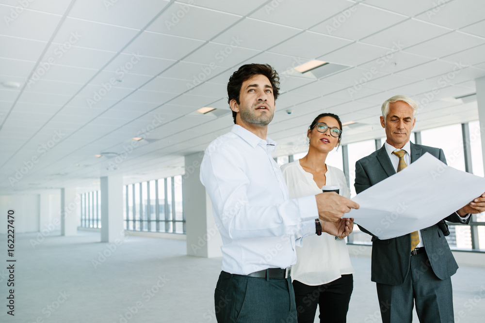 Estate agent and clients with blueprints of new office space