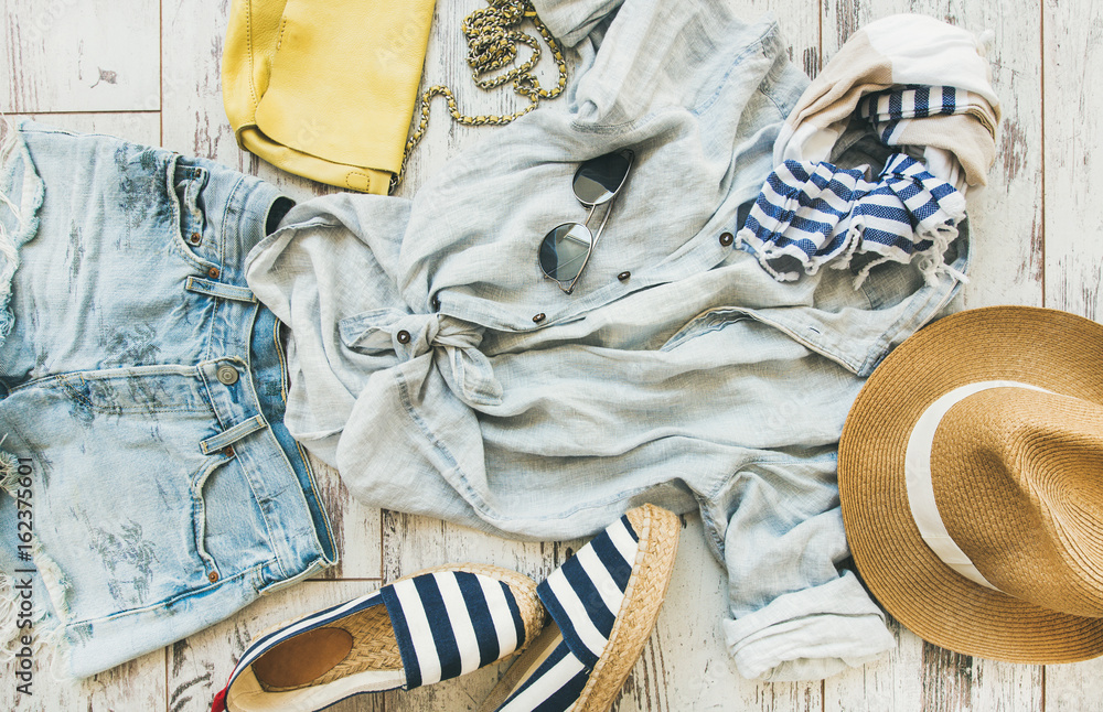 Summer outfit flatlay. Pastel summer womens clothes, parquet background, top view. Blue denim short