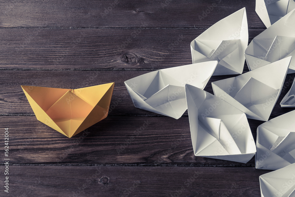 Business leadership concept with white and color paper boats on 