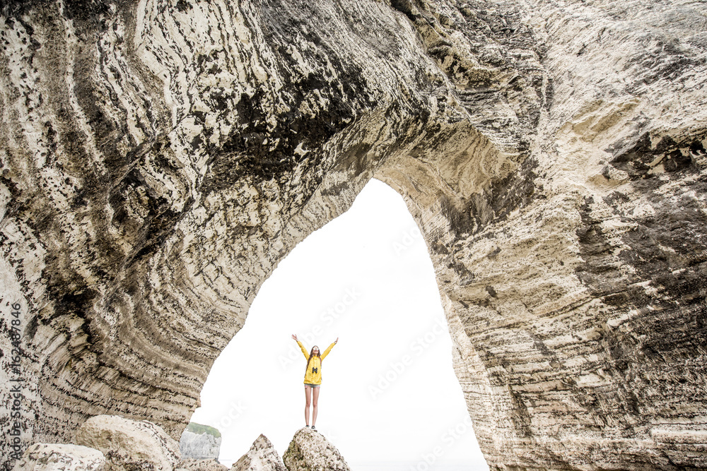 巨石峭壁上的景观，有一个洞，里面站着旅行者