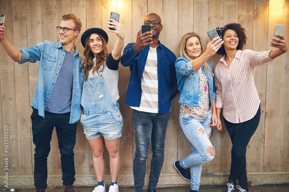 Happy friends taking selfie at wooden wall