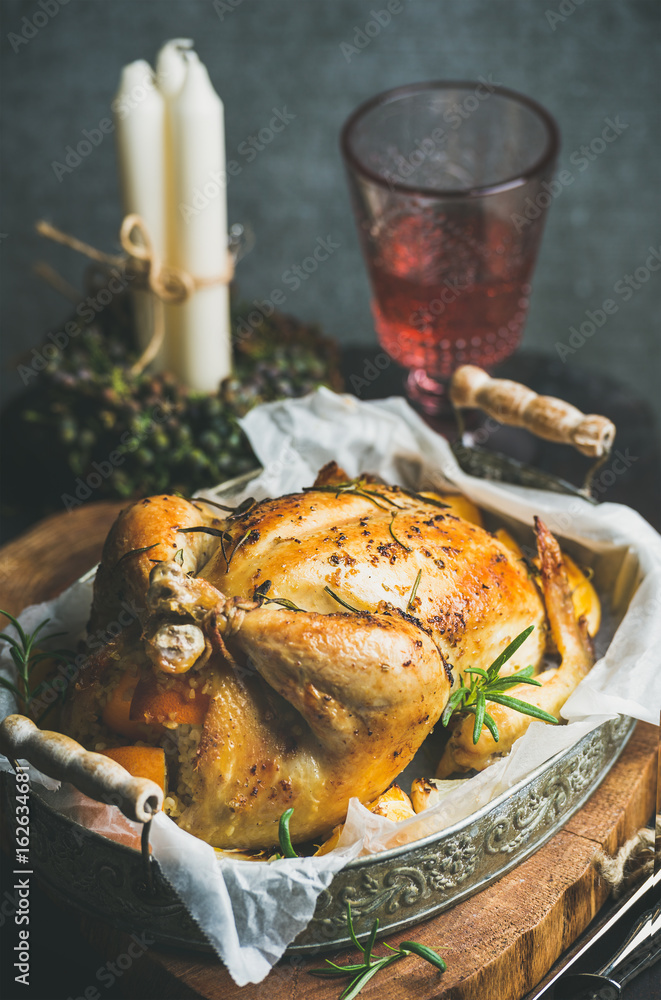 Christmas holiday table set with oven roasted whole chicken with oranges, bulgur, rosemary, decorati