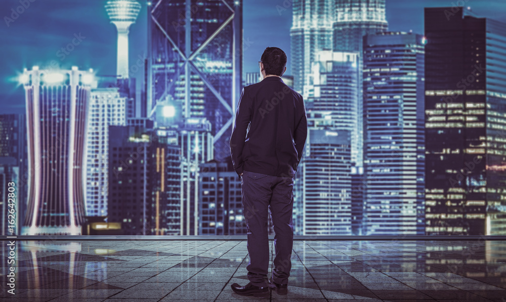 Rear view of indecisive businessman with blurred morden city skyline .