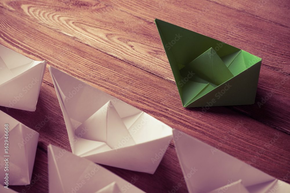 Business leadership concept with white and color paper boats on 