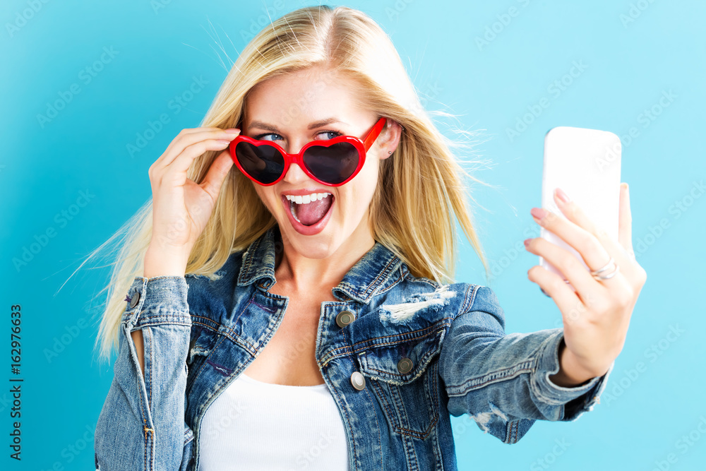 Young woman taking a selfie on a blue background