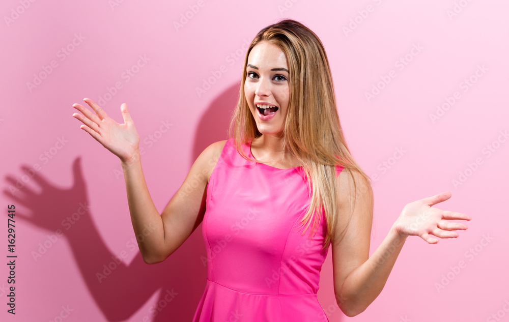 Surprised young woman posing on a pink background