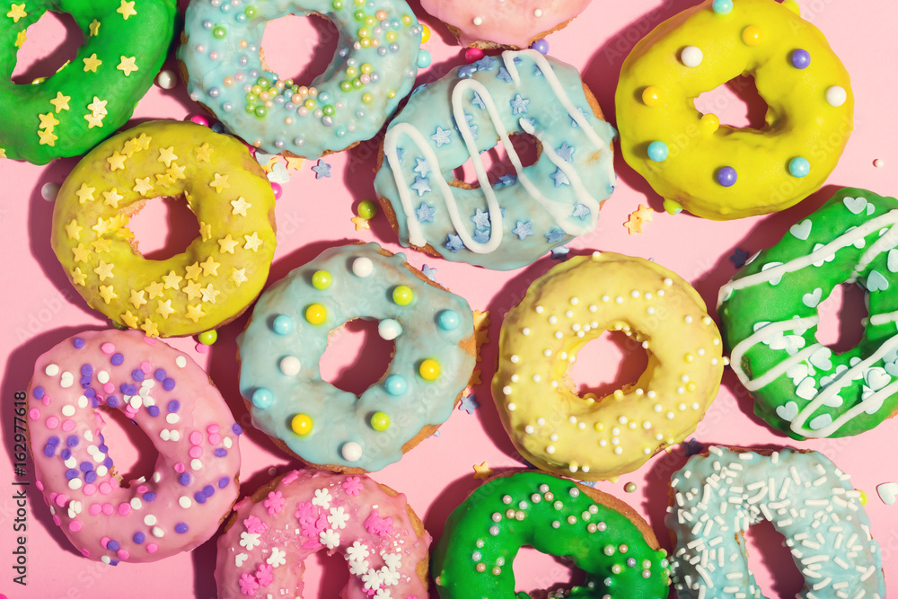 Colorful glazed donuts on a pink background