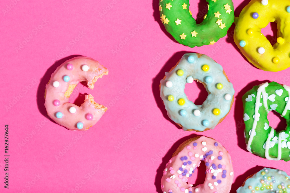 Colorful glazed donuts on a pink background