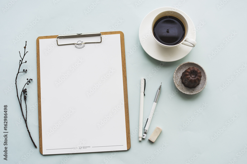 Aerial view of paper clipboard with coffee cup and cake