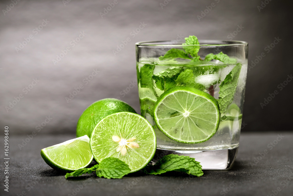 Close up the fresh mojito cocktail with fresh lime and mint leaf on black stone background