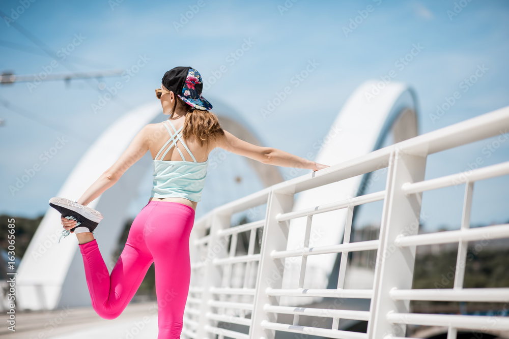 身穿鲜艳运动服的年轻女子在里昂市白色现代桥上户外锻炼