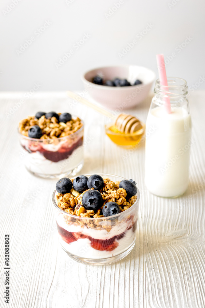 Cooking breakfast with granola and berries on white kitchen back