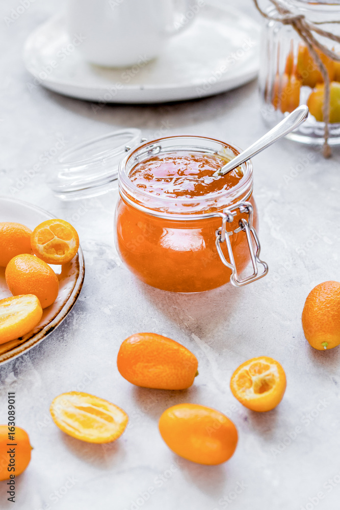 kumquat on plate and jam in jar at gray background