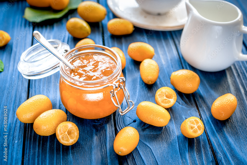 kumquat on plate and jam in jar at wooden table