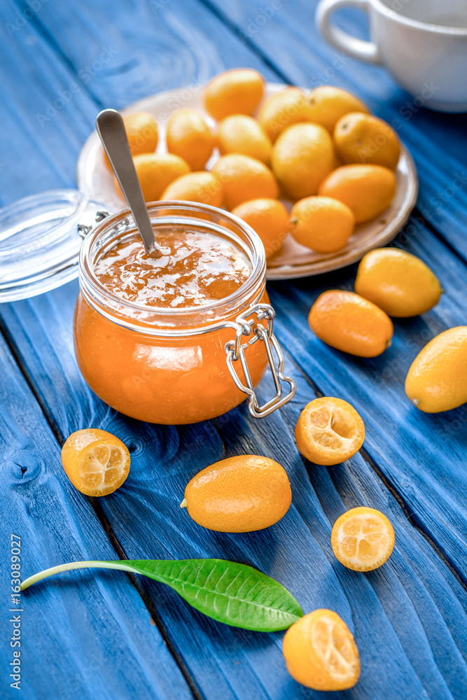 kumquat on plate and jam in jar at wooden table